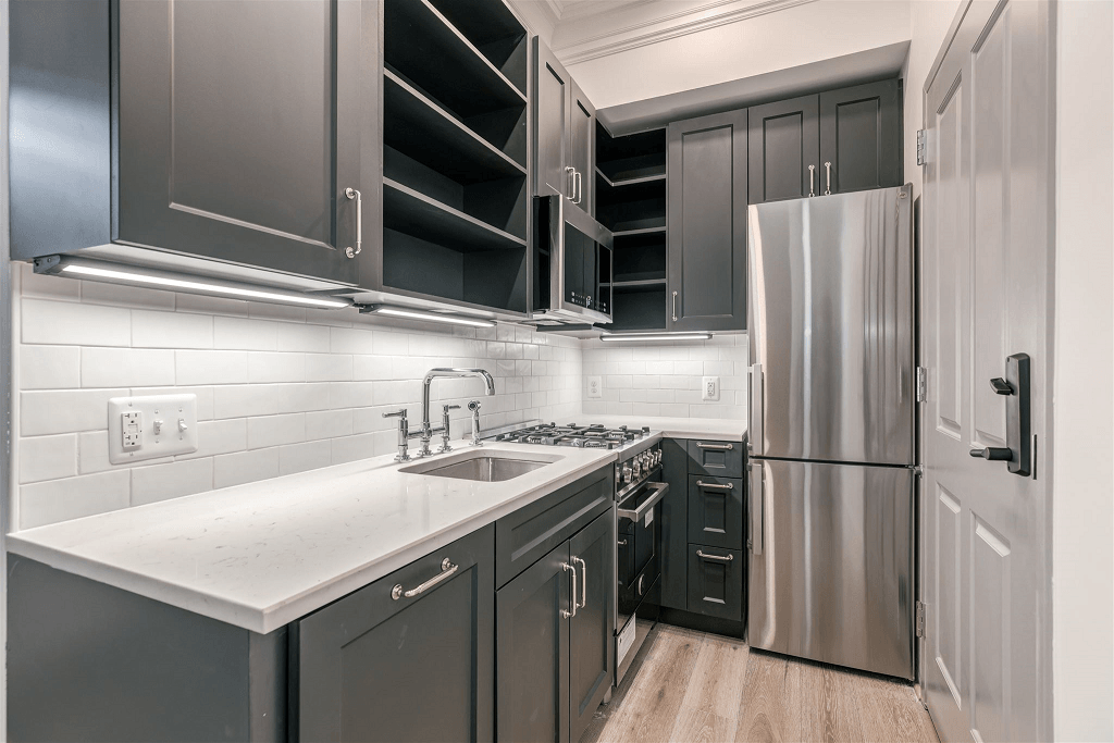a kitchen with black cabinets and a stainless steel refrigerator